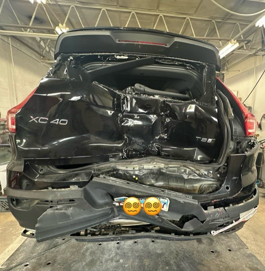 A severely damaged black Volvo XC40 SUV, rear end crushed.