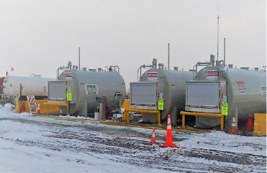 A row of fuel tanks are lined up in the snow.