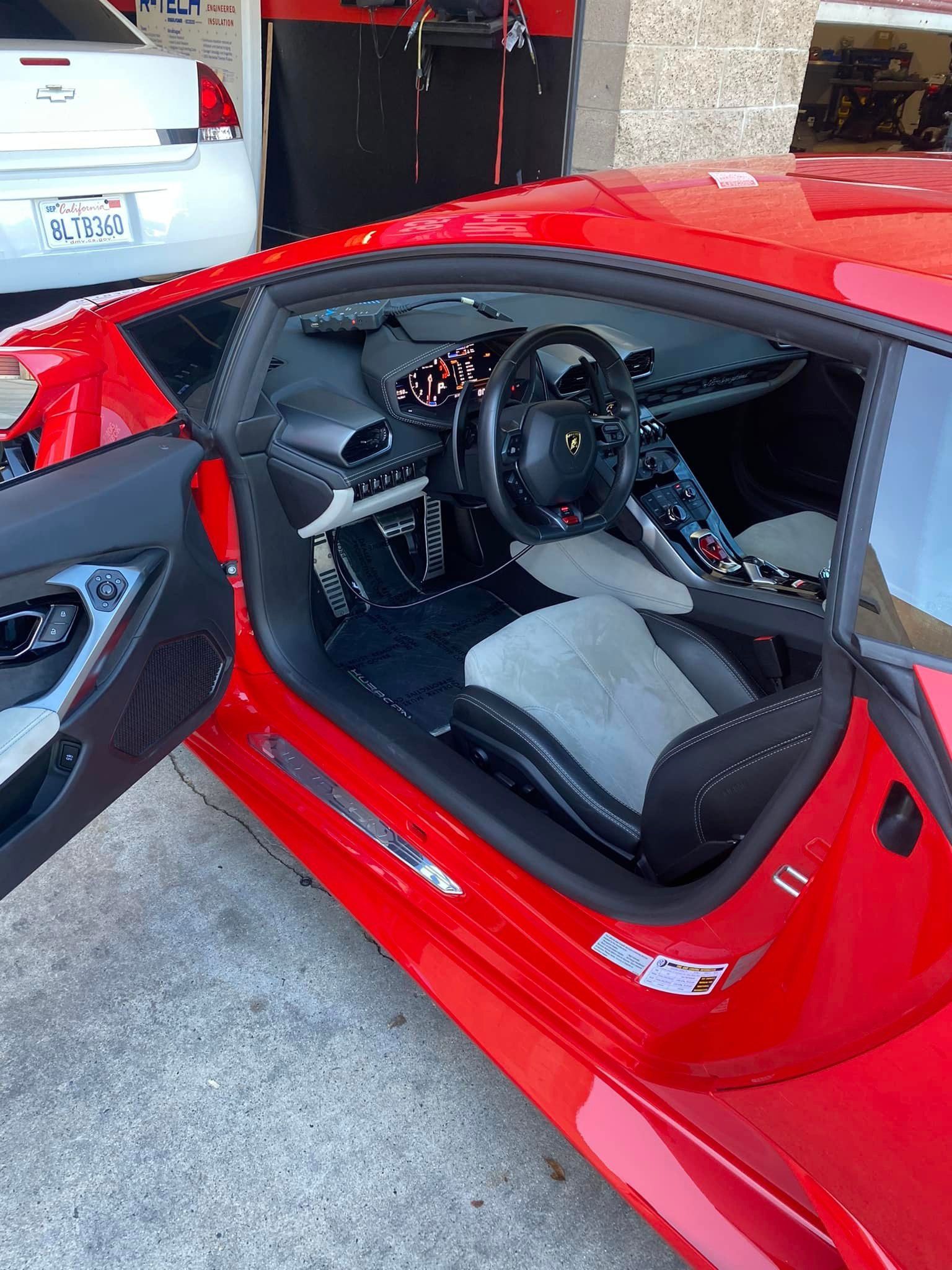Red Lamborghini sports car with the door open, revealing a black and grey interior.
