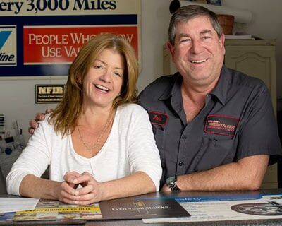 A man and a woman are posing for a picture in front of a sign