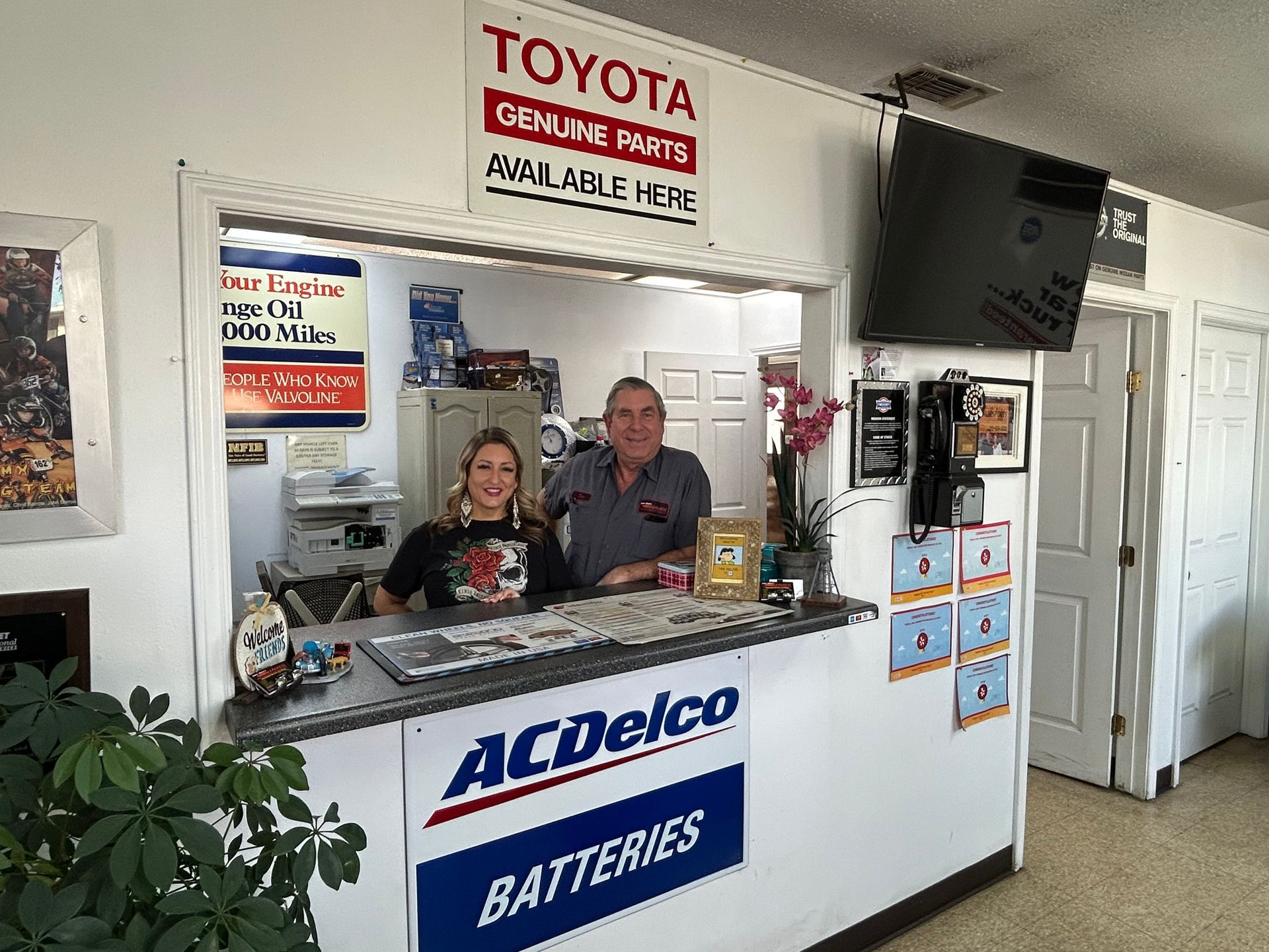 A man and a woman are standing behind a counter in a Toyota and Acdelco store