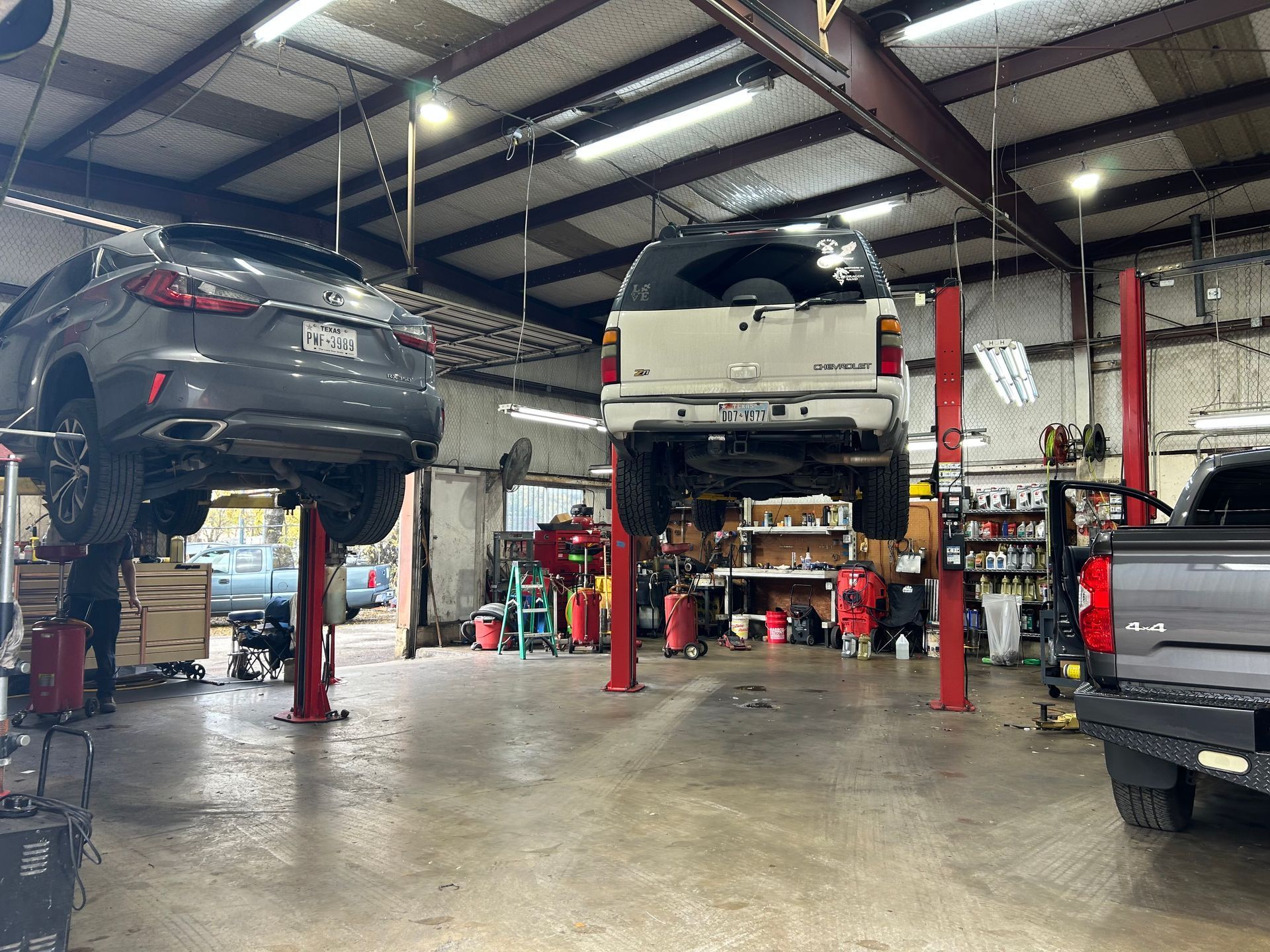 Two cars are sitting on lifts in a garage