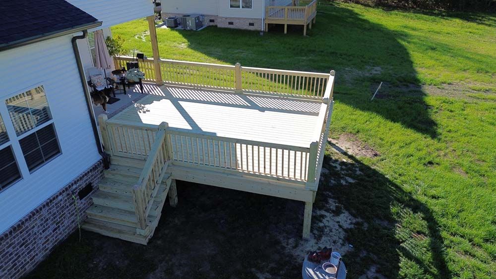 Wooden deck extension attached to a house with stairs.