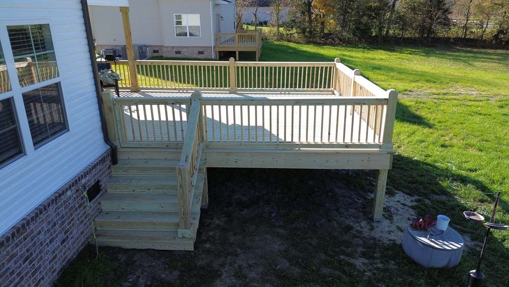 Newly constructed wooden deck with stairs in a backyard.
