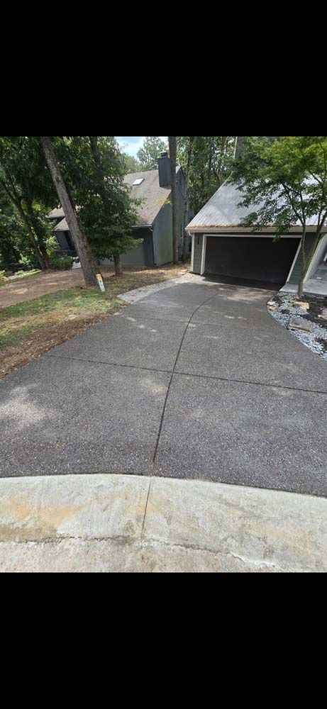 Driveway leading to a house with a garage, trees on the side, overcast day.