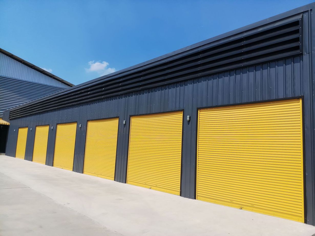 Industrial building with yellow garage doors and dark siding under a blue sky