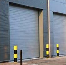 Gray warehouse doors with yellow-and-black bollards in front