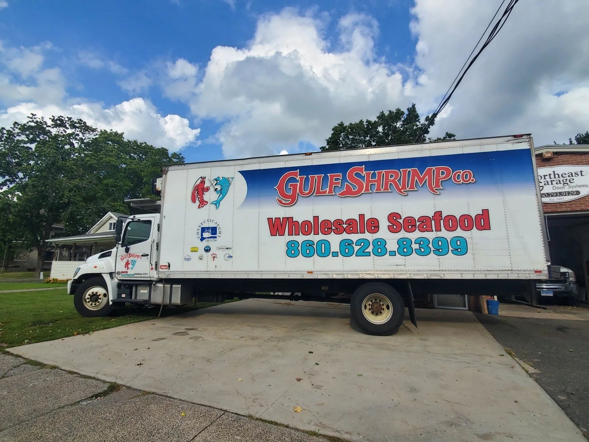 White box truck with “Gulf Services” and contact info parked on a driveway under a blue sky