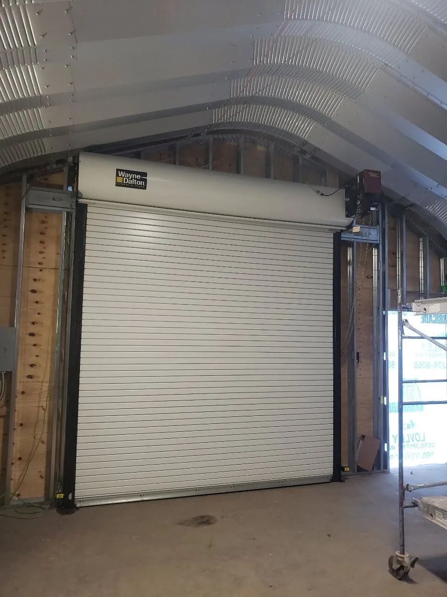 Interior of a metal storage unit with a closed white roll-up door and concrete floor