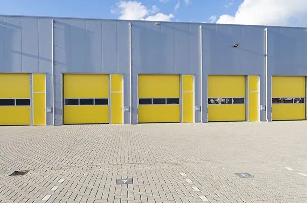Yellow loading bay doors on a gray industrial building under a blue sky