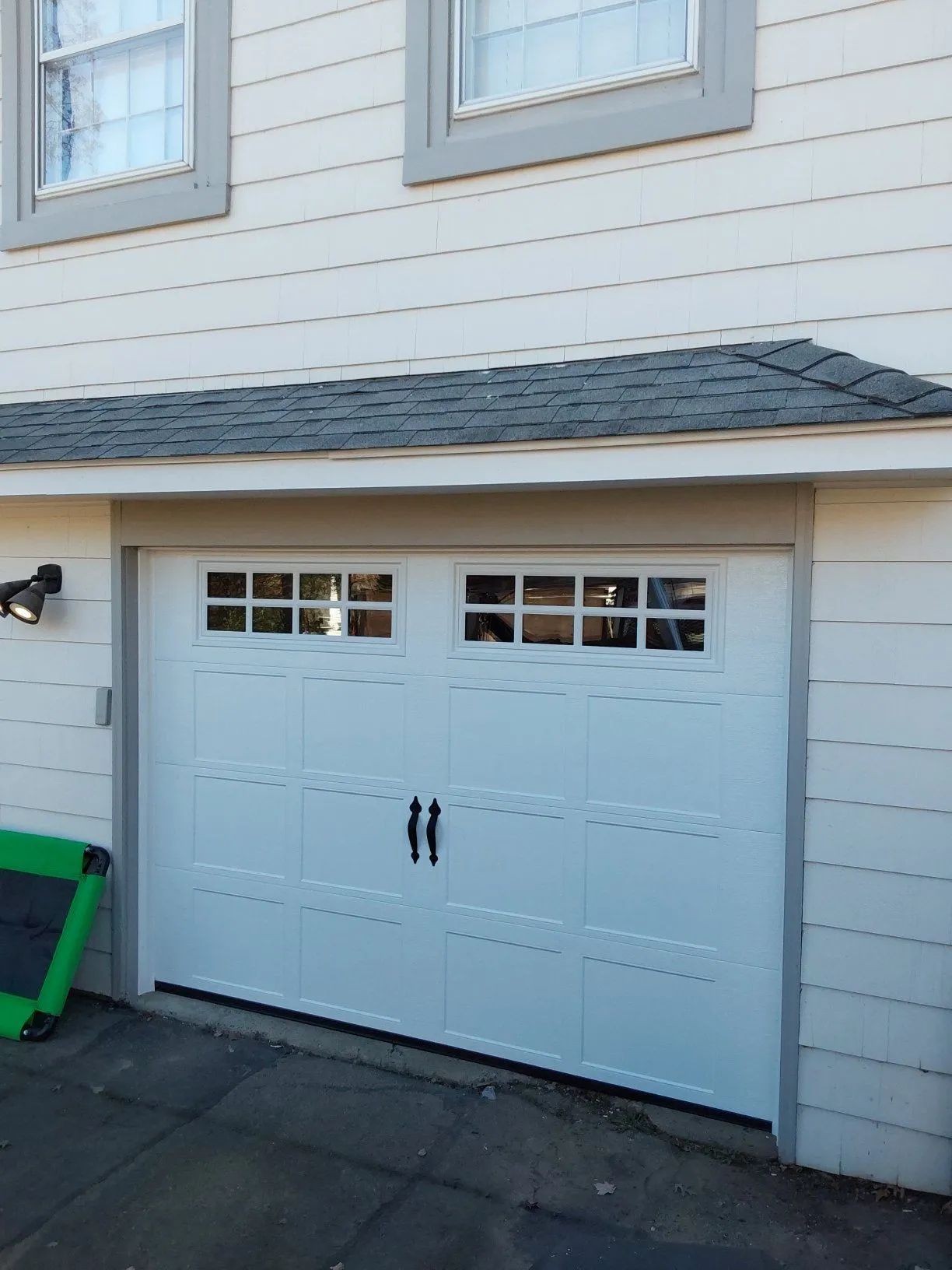 White double garage doors on a house exterior with small windows and black handles