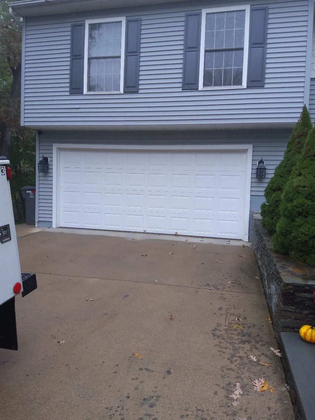 Suburban house with a white garage door and driveway on a cloudy day