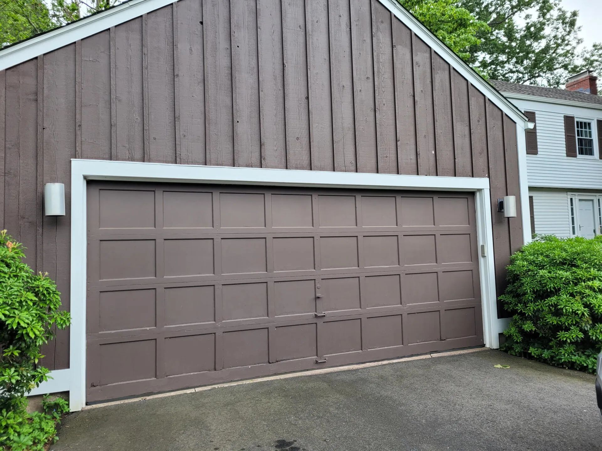 Brown garage with white trim and a sloped driveway in a suburban setting