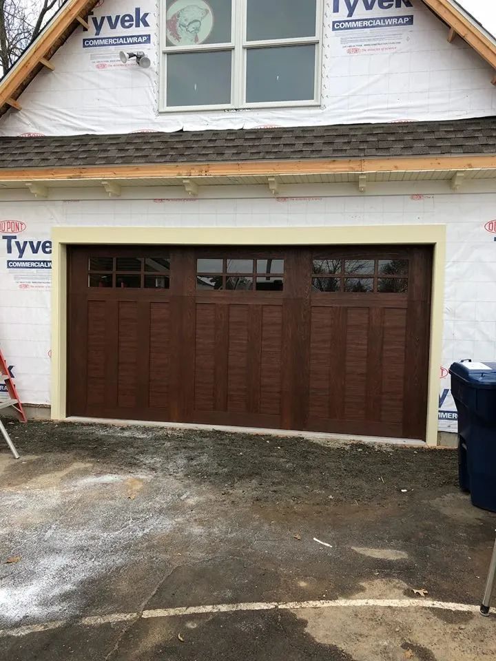 House exterior with a brown garage door under construction, wrapped in Tyvek siding.