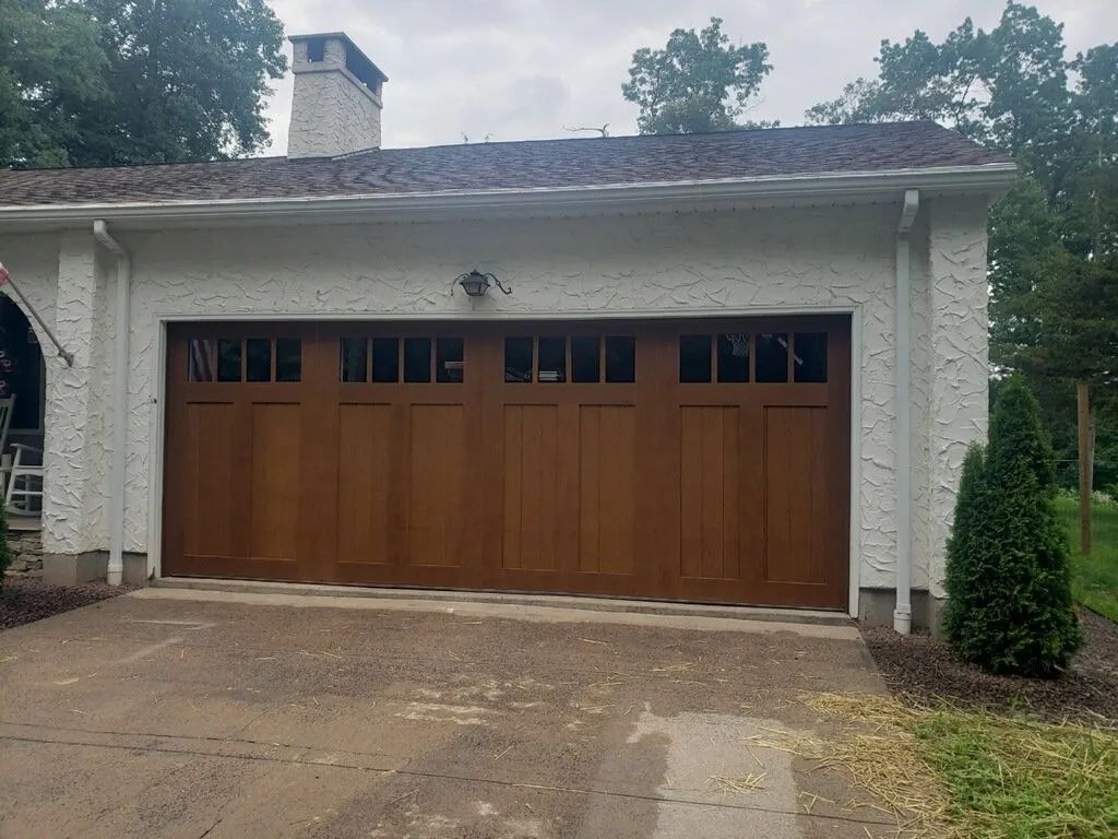 Two-car garage with brown wooden doors on a stucco house, viewed from the driveway