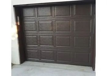 Closed brown garage door on a white exterior wall with a concrete driveway.
