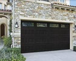 Black garage door on a stone house exterior with a driveway in front