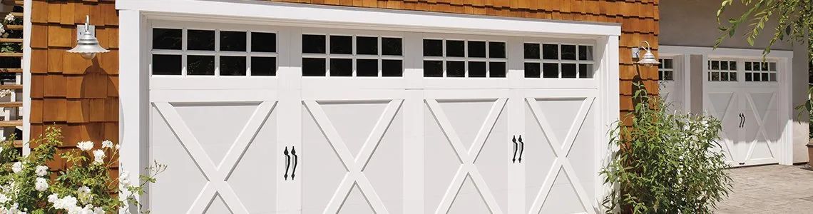 White double garage doors on a brick house with white trim and greenery nearby