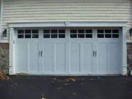 White double garage doors on a house with small windows above them.