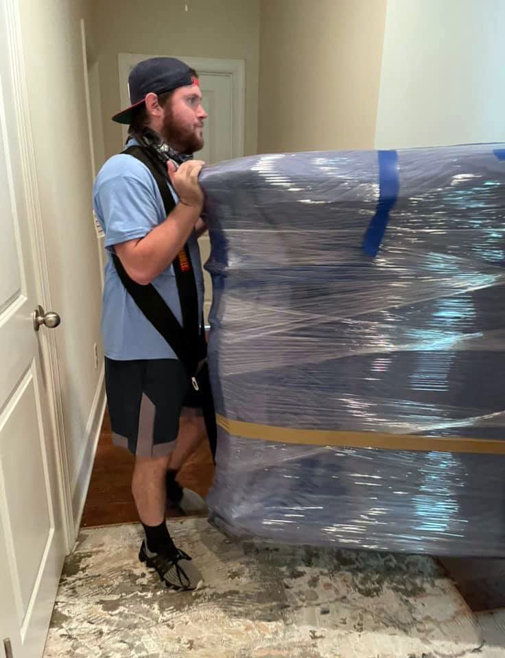 a man is carrying a large piece of furniture wrapped in plastic