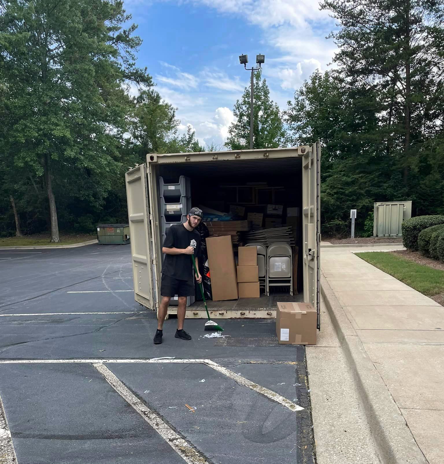 a man standing in front of a container filled with boxes and chairs
