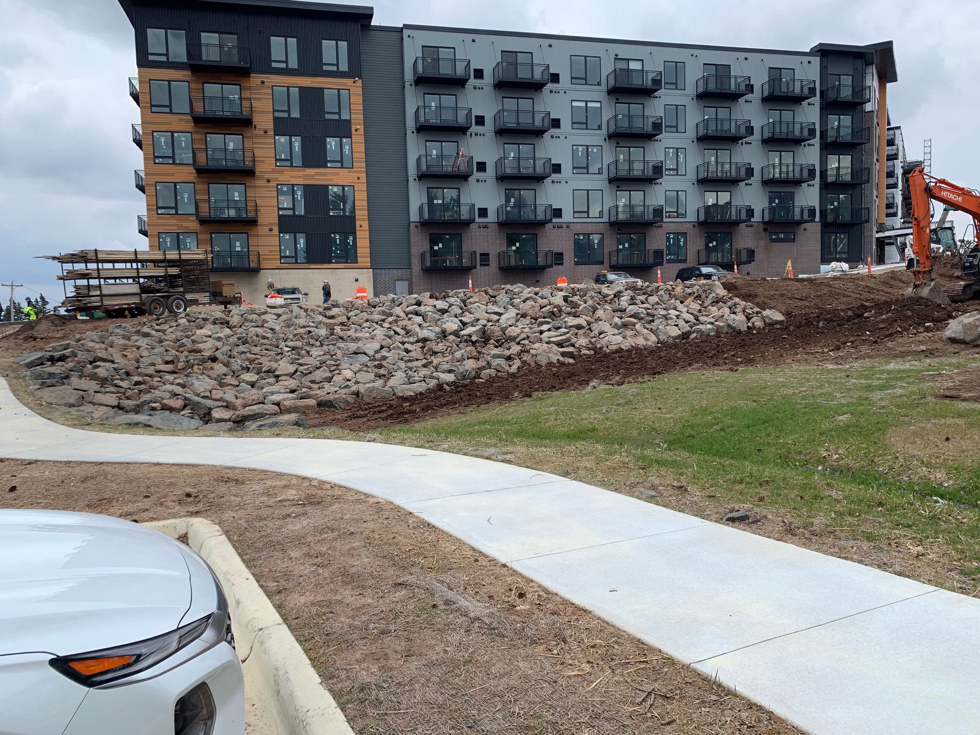 A white car is parked in front of a building under construction