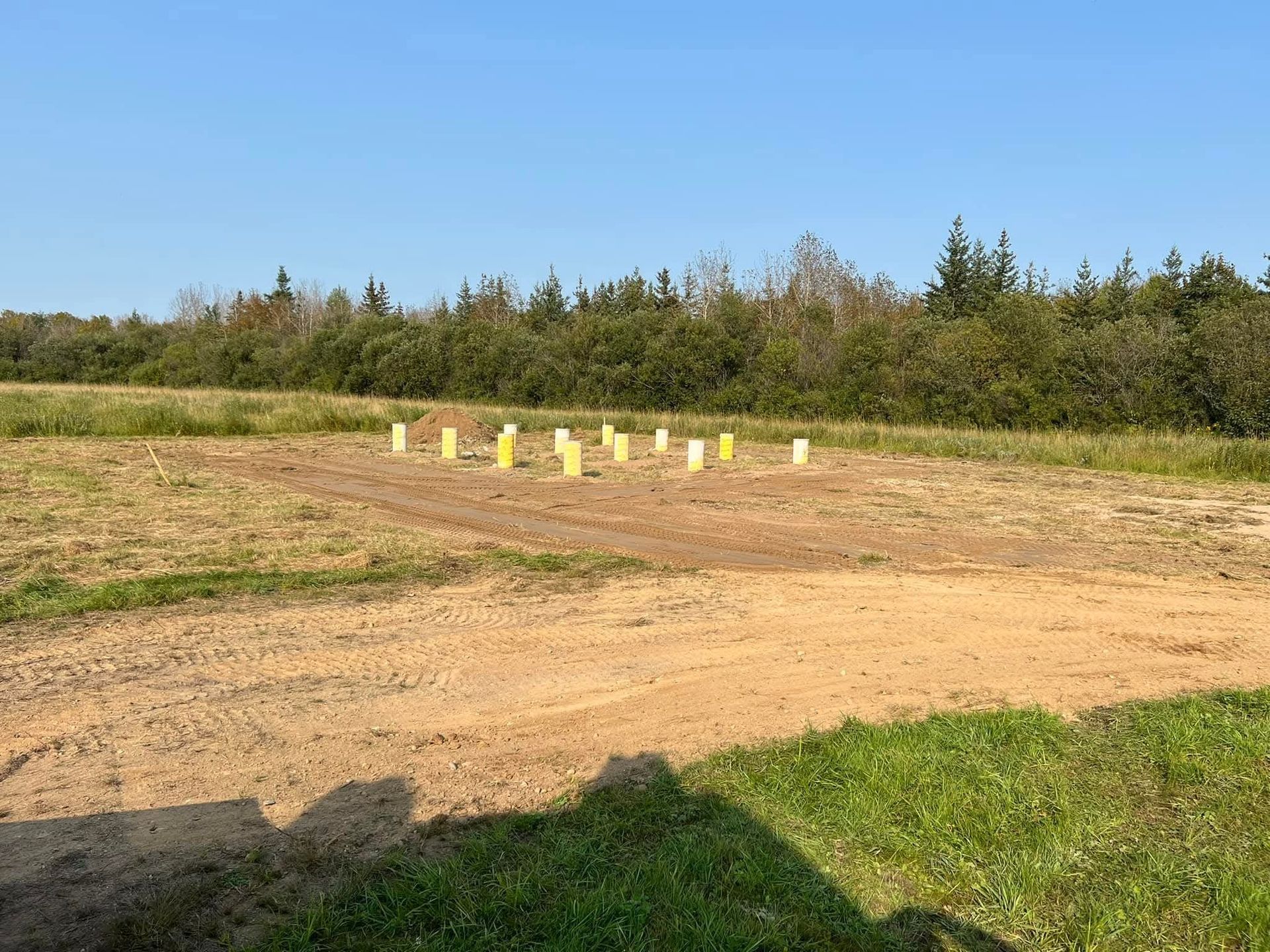 A field with a row of yellow poles in the middle of it.