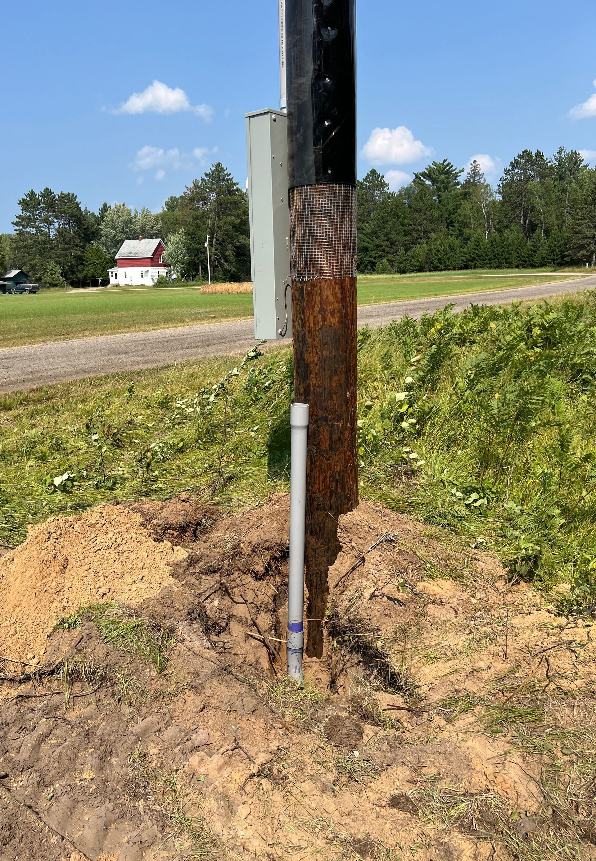 A rusty pole is sitting in the middle of a grassy field.