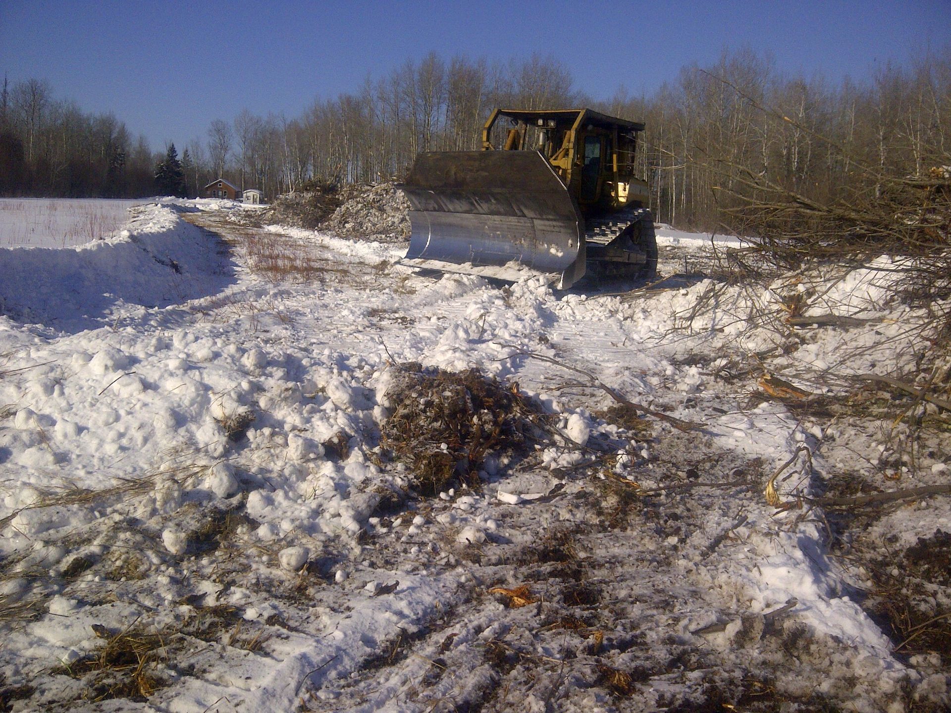 A bulldozer is driving through a snowy field