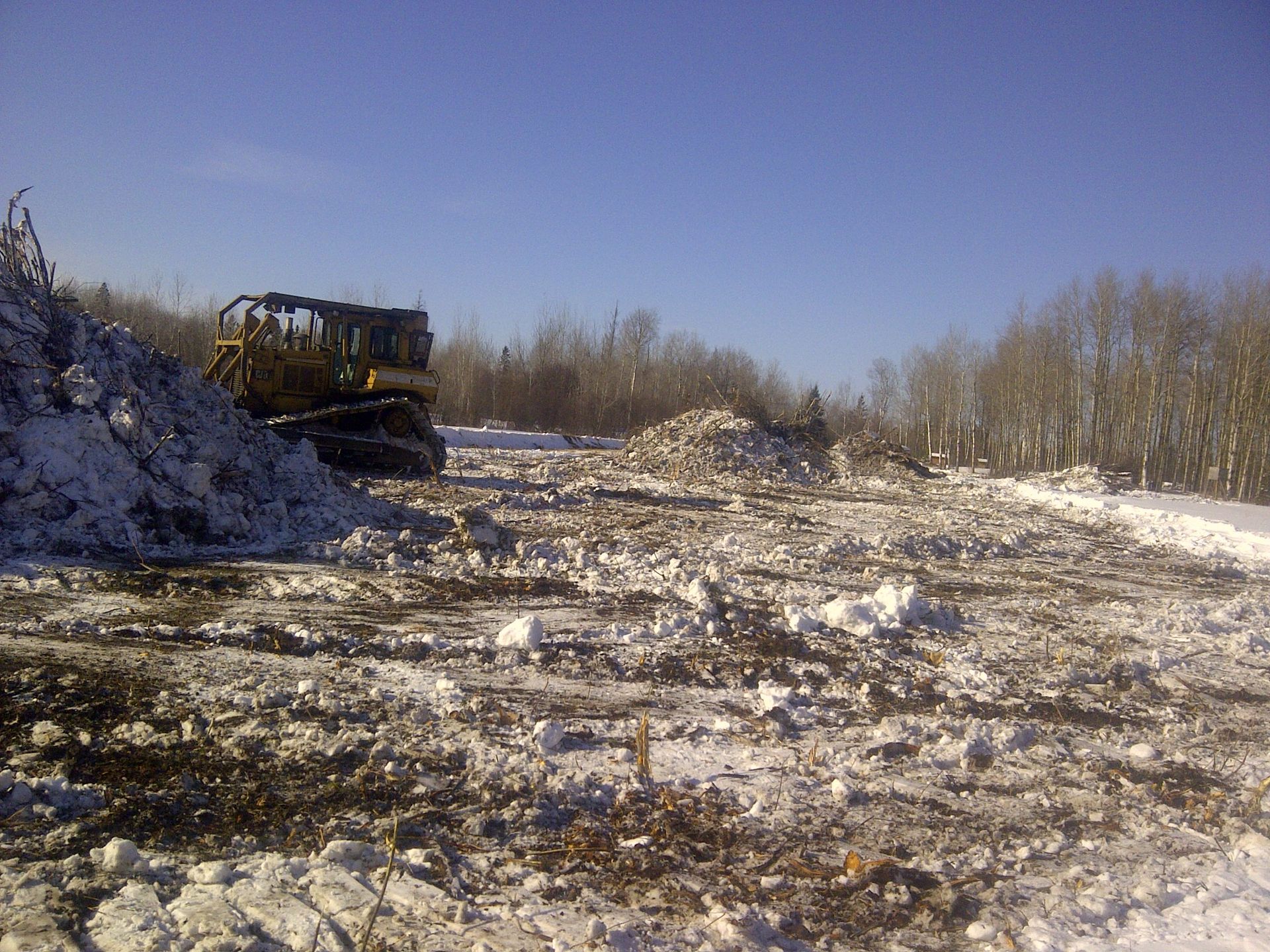 A bulldozer is driving down a snowy road.