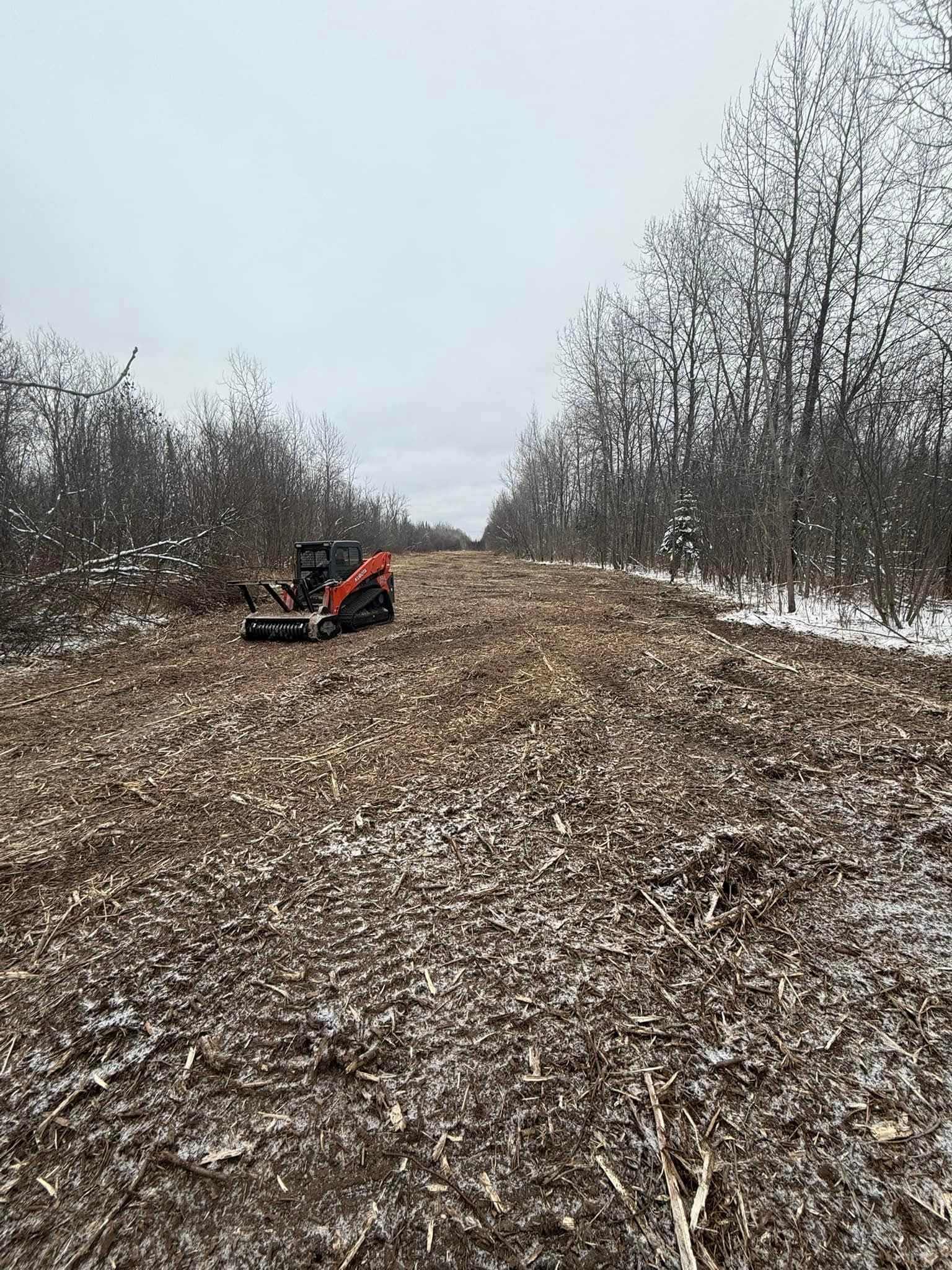 A tractor is driving down a dirt road in the middle of a field.