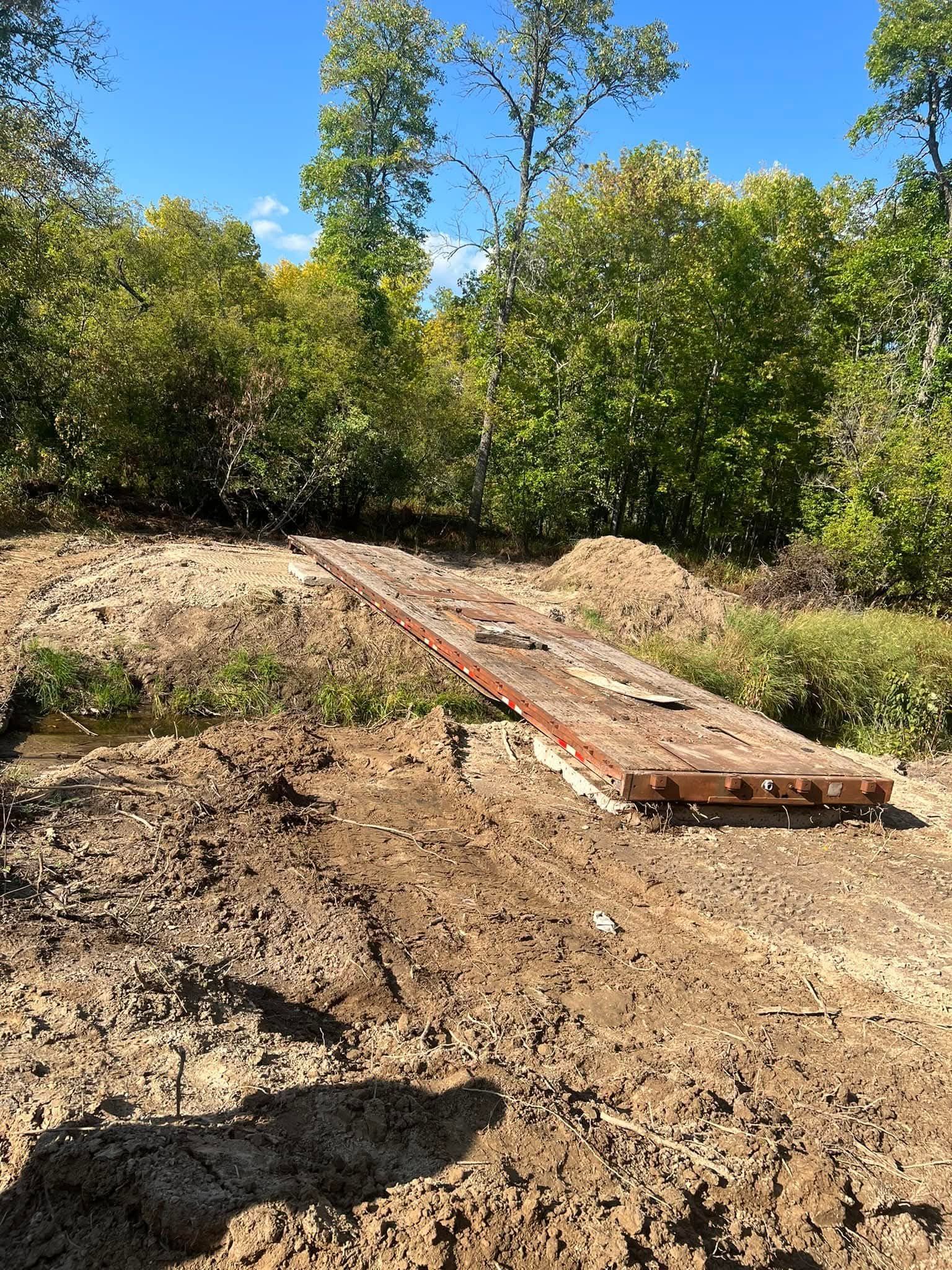 A wooden bridge is being built over a muddy river.