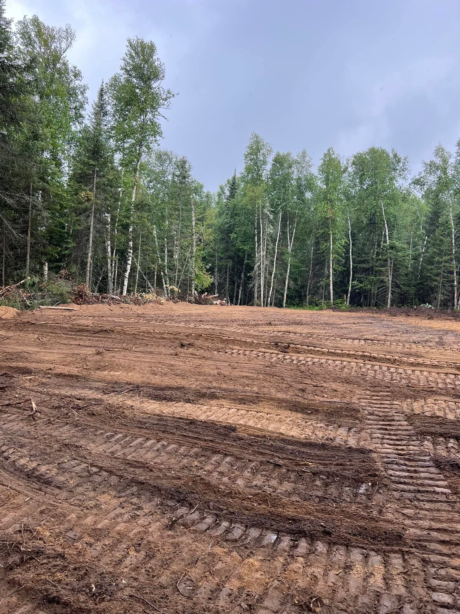 A large dirt field with trees in the background.