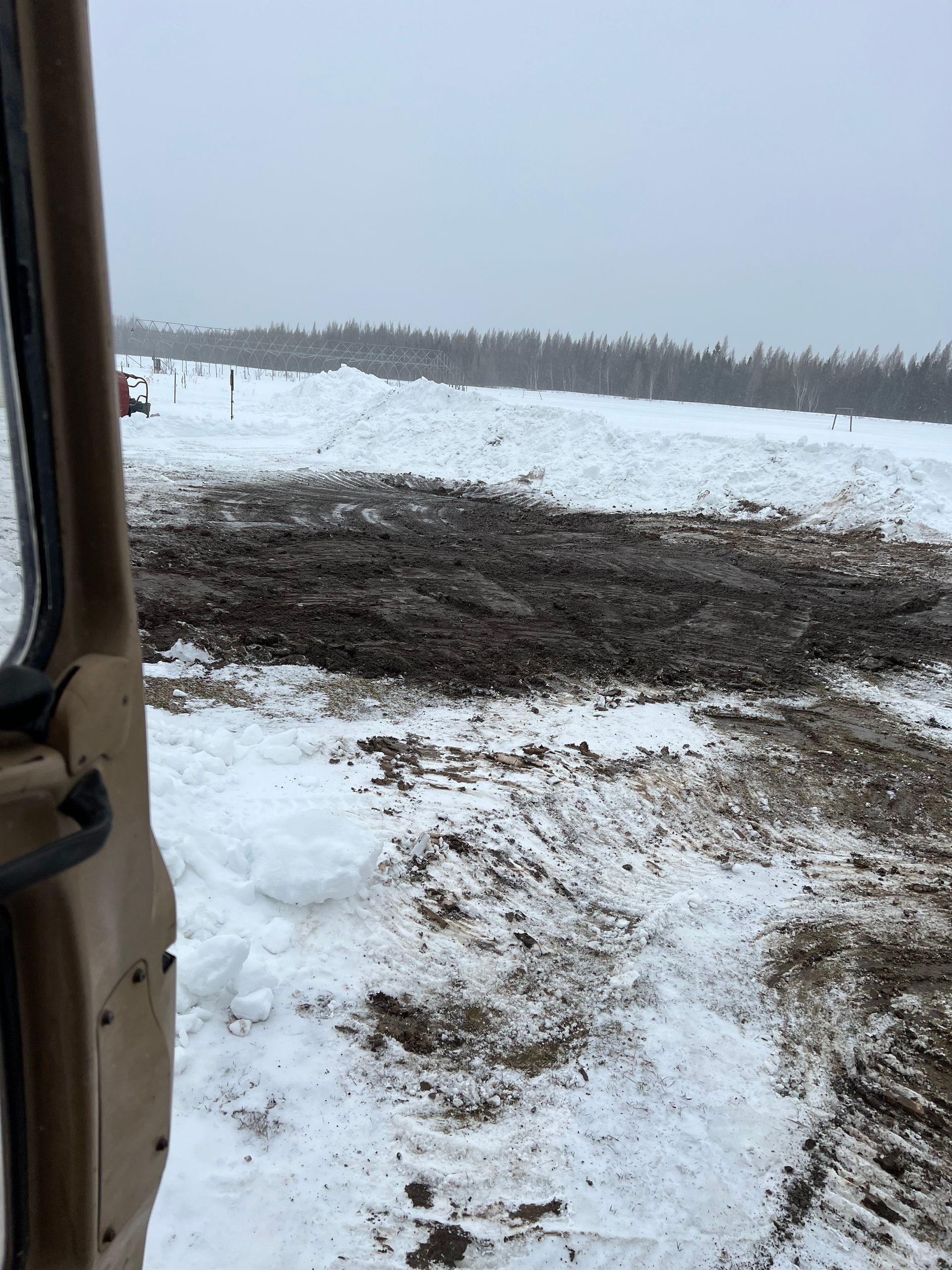 A truck is driving through a snowy field.