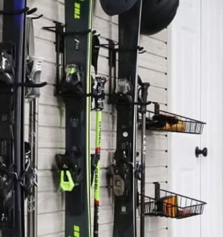 Ski equipment organized on a wall rack with skis, poles, and baskets for storage.