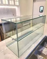 Clear glass display case with two shelves on a white countertop, likely in a commercial kitchen.