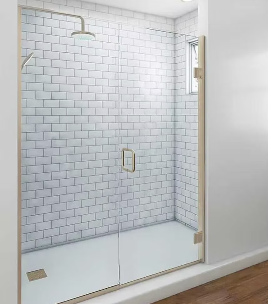 Modern shower with glass door, white subway tile walls, and brass fixtures.
