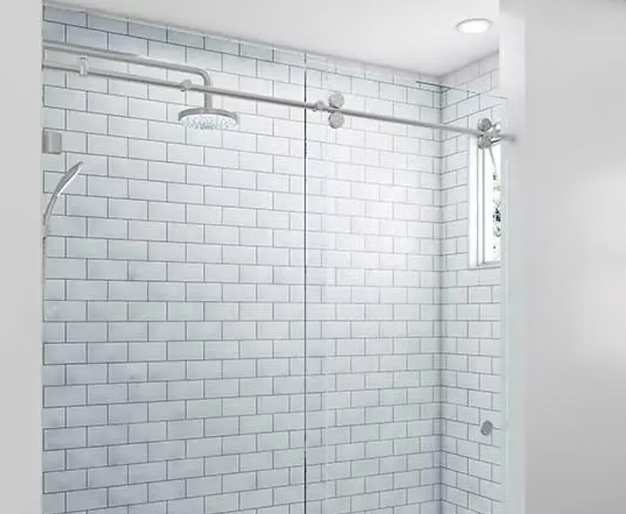 Shower with glass doors, white subway tile walls, and a silver shower head.
