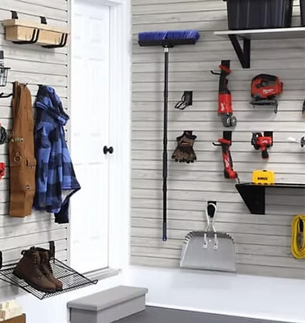 Garage wall with organized tools and coats on slatwall.