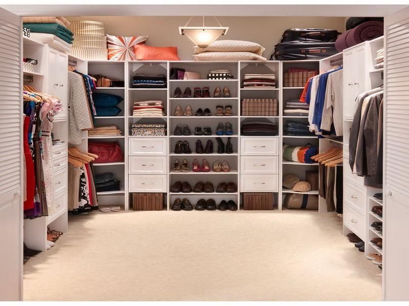 Walk-in closet with white shelves and storage; clothes, shoes, and accessories neatly organized.