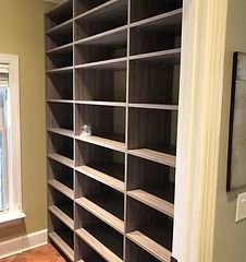 Built-in gray shelves in a room, next to a doorway and window. Shelves are empty.