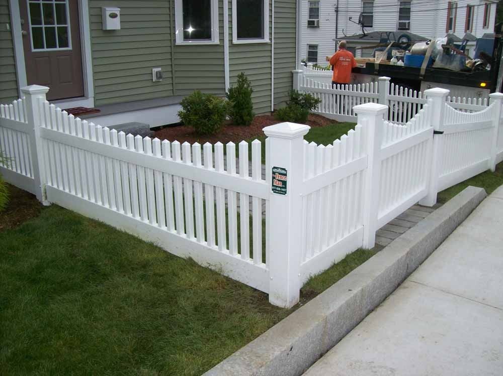 White picket fence enclosing a small corner yard beside a house and sidewalk