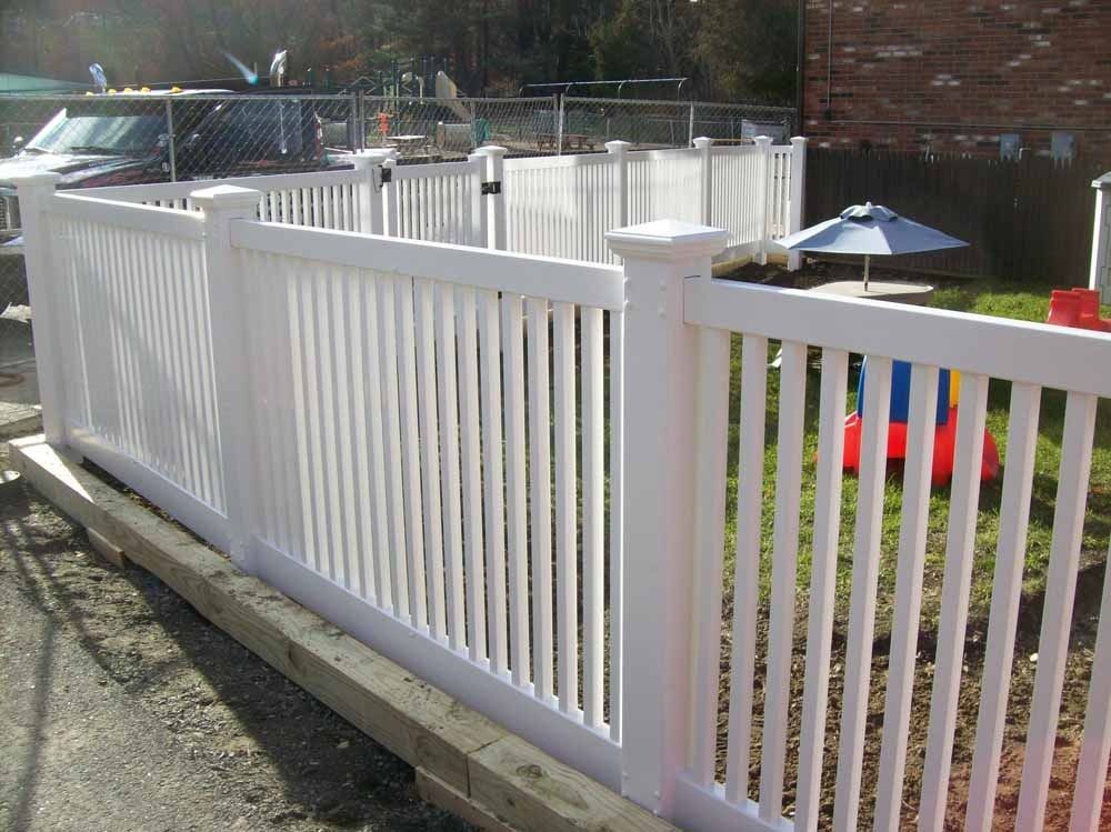 White vinyl fence along a yard with patio furniture and a small umbrella.