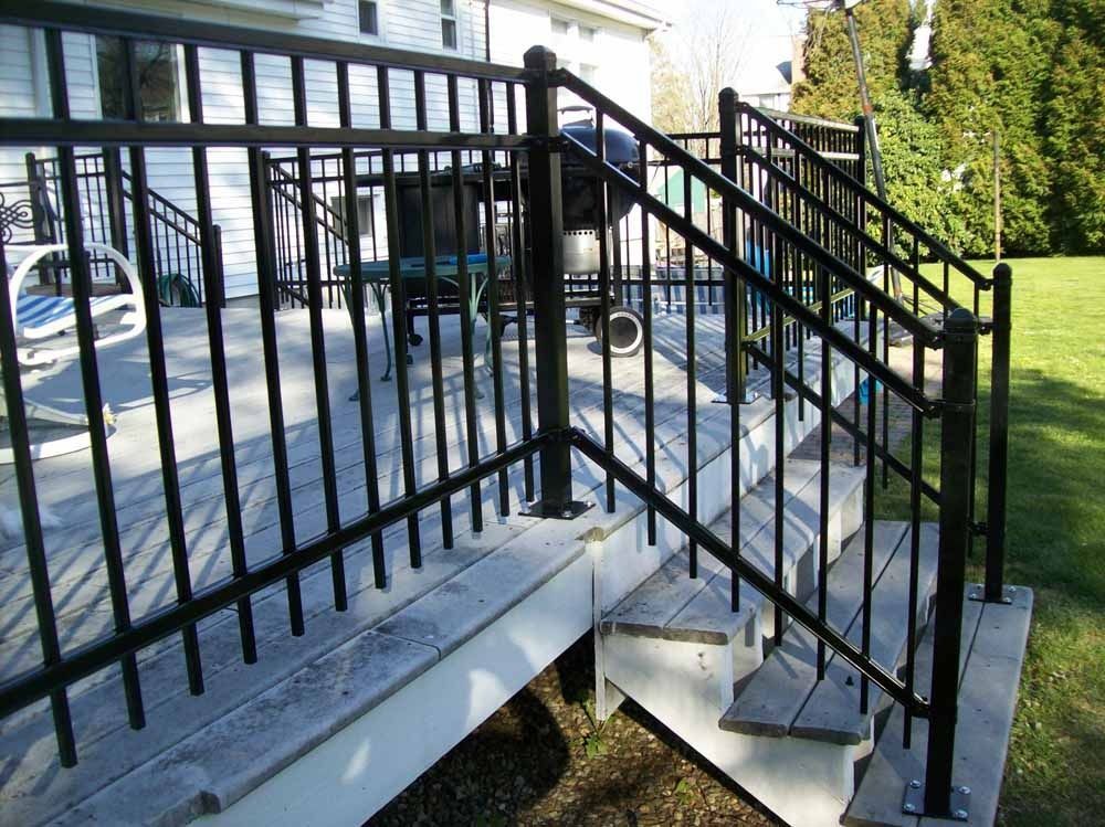 Black metal stairway with handrails beside a raised deck and grassy yard outdoors