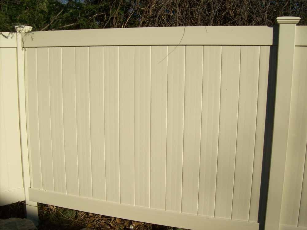 White vinyl privacy fence with a post in a grassy outdoor yard