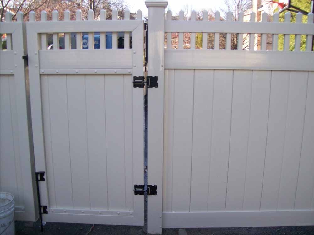 White double gate with a central post and latch, viewed from the street in front of a house.
