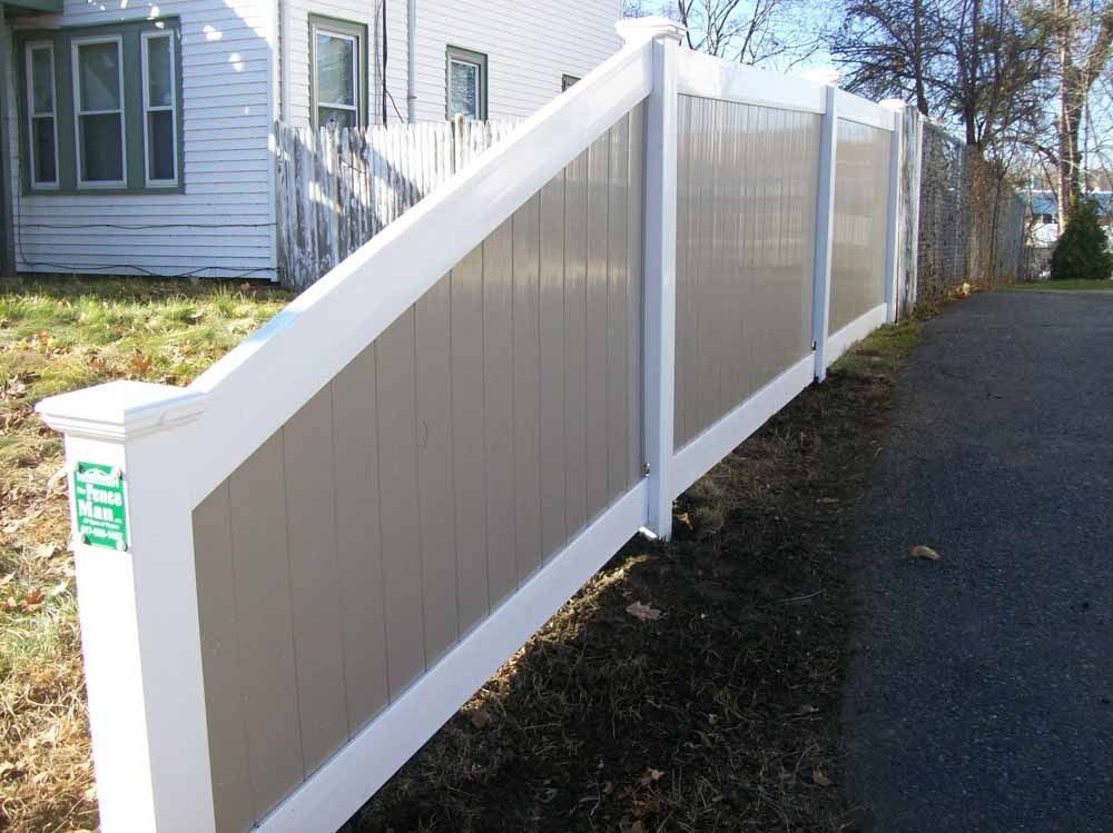 White vinyl fence along a driveway beside a house and gravel path