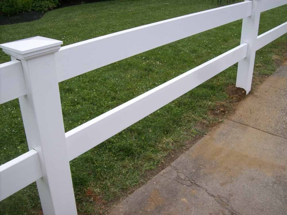White wooden fence bordering a grassy yard beside a concrete sidewalk