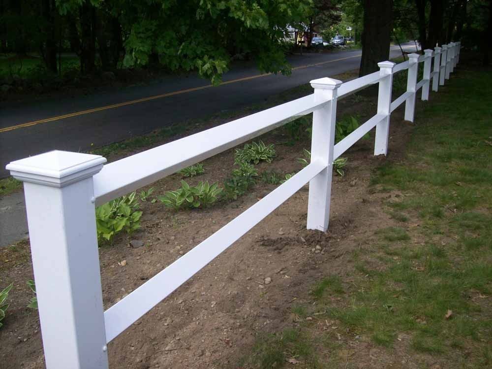 White wooden fence along a roadside path beside trees and grass