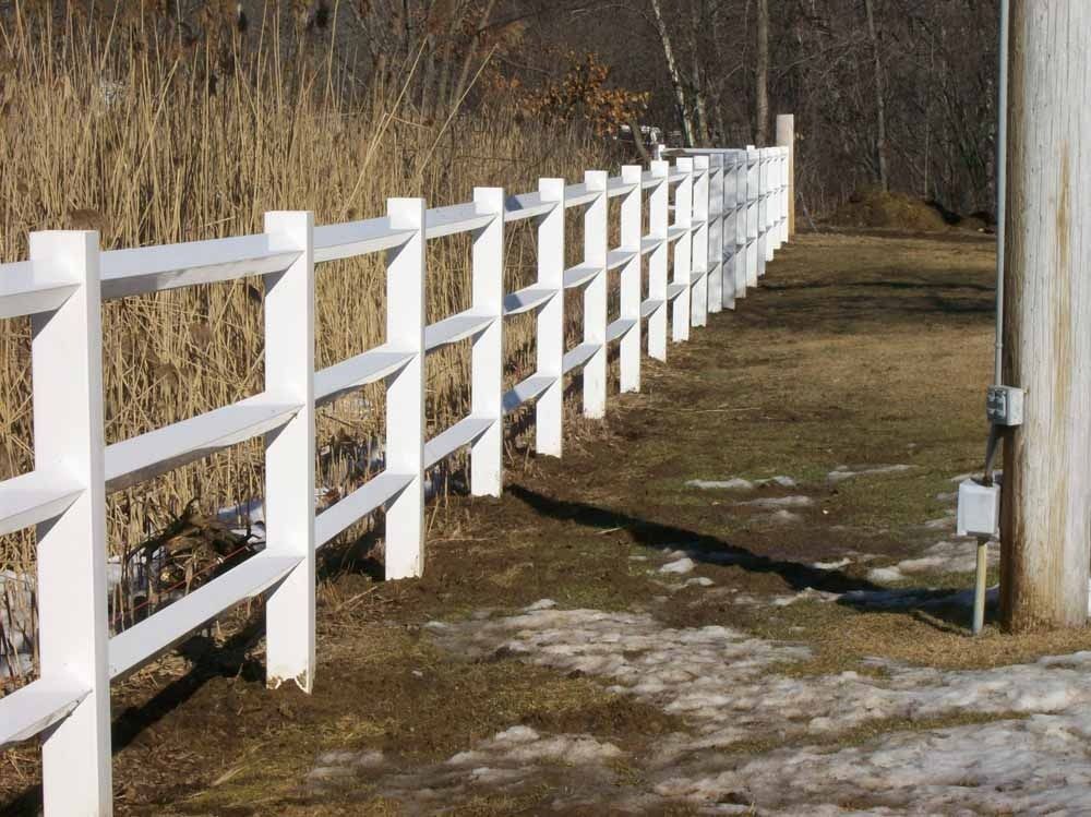 White wooden fence along a dirt path beside dry grass and trees
